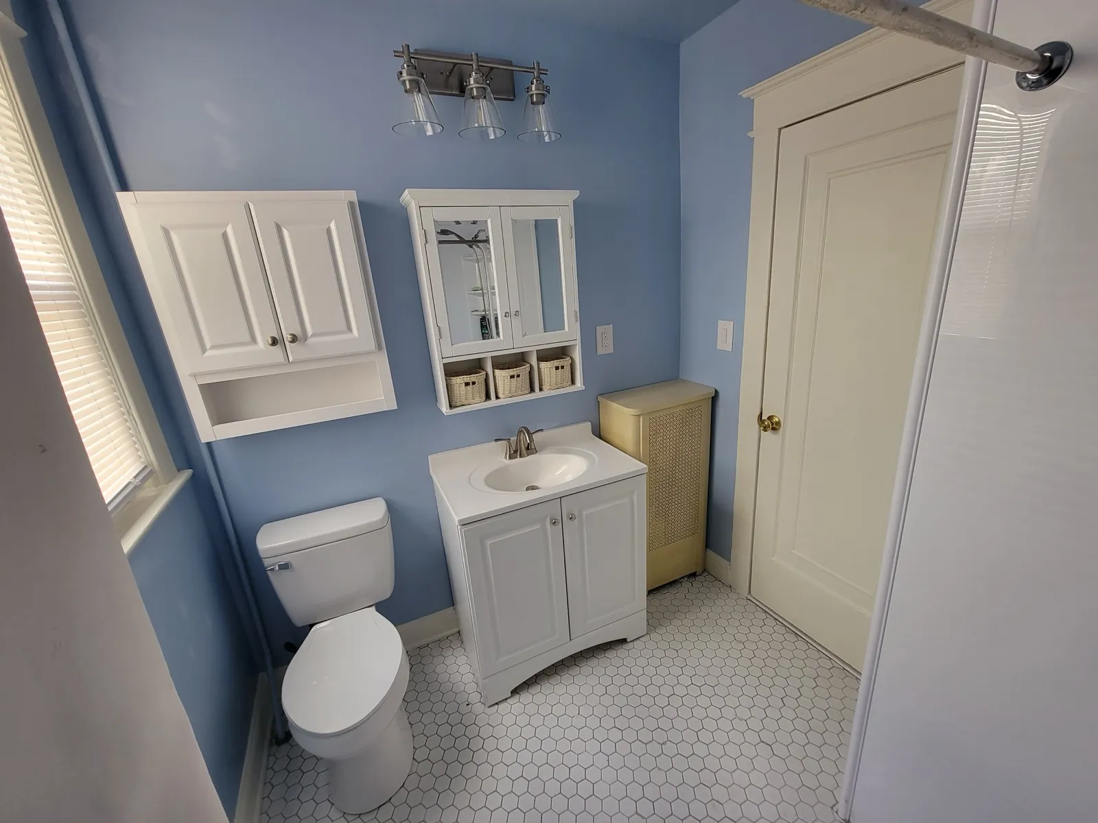 Refreshed hall bathroom with a new white vanity, toilet, medicine cabinet and hex tile floor