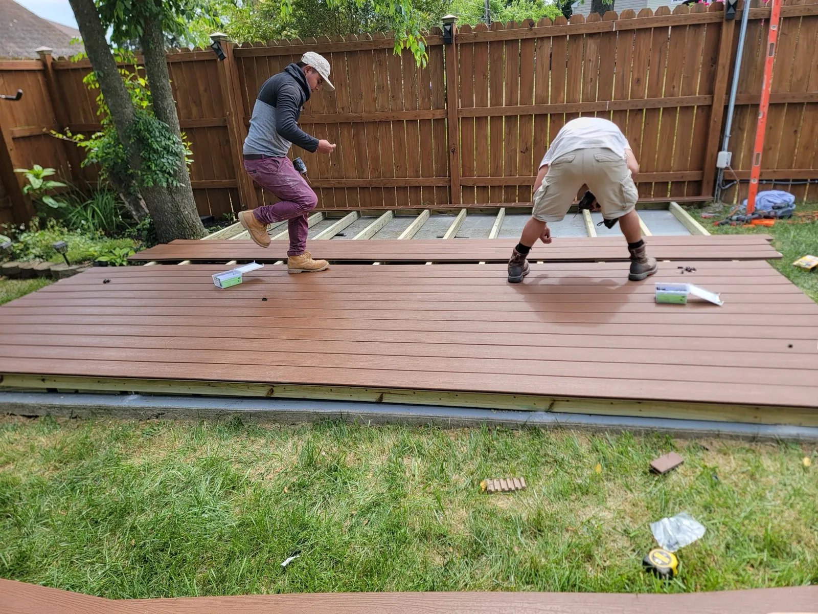 Crew installing composite deck boards over a wood frame