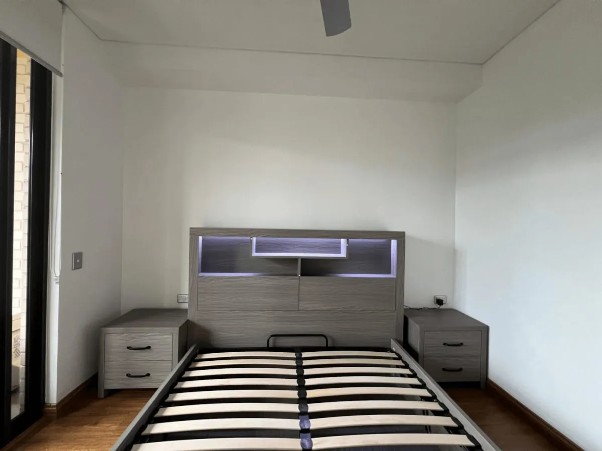 Assembled bed frame with a headboard and two nightstands in an empty bedroom