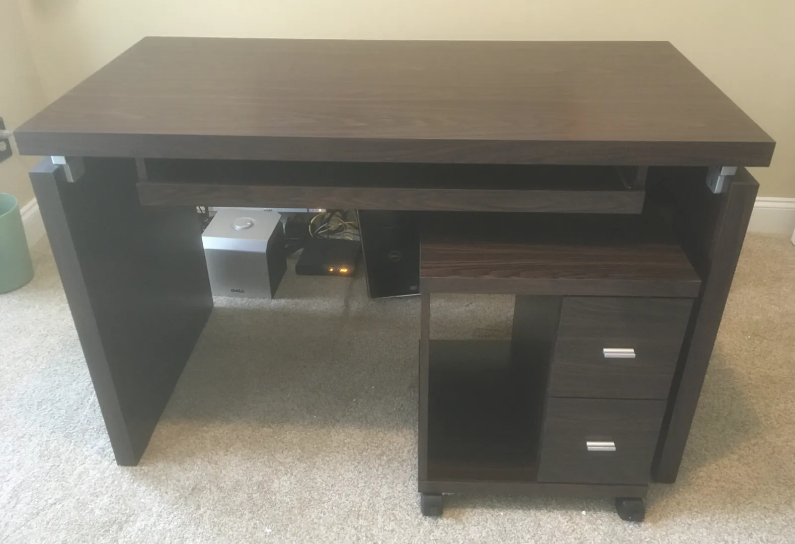 Assembled dark wood desk with a keyboard tray and a rolling drawer unit