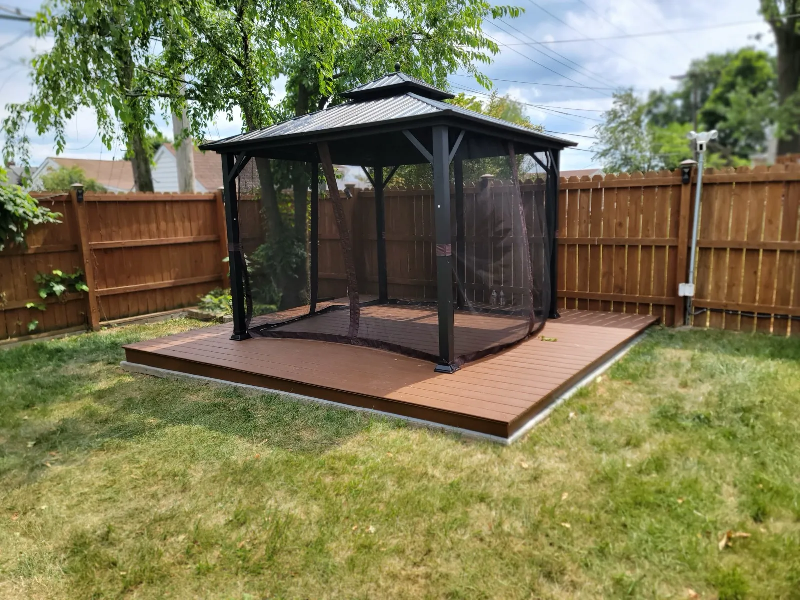 Screened gazebo assembled and installed on a backyard deck