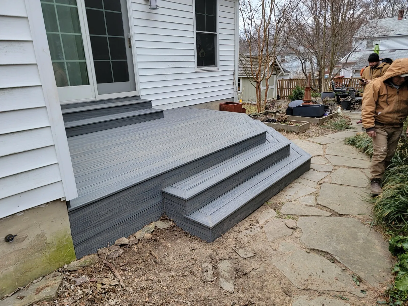 Composite deck with steps and stone walkway behind a home